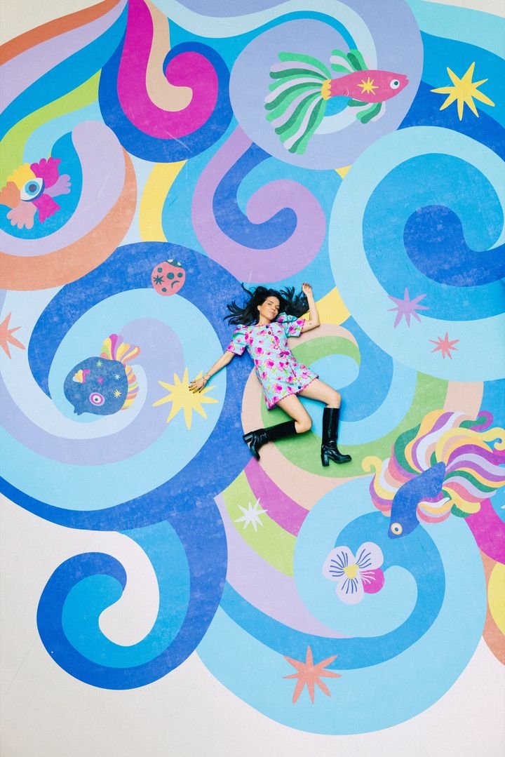 L'illustratrice Léona Rose pose sur une fresque qu'elle a réalisé ans le centre commercial Beaugrenelle, avril 2026. (BEAUGRENELLE PARIS)