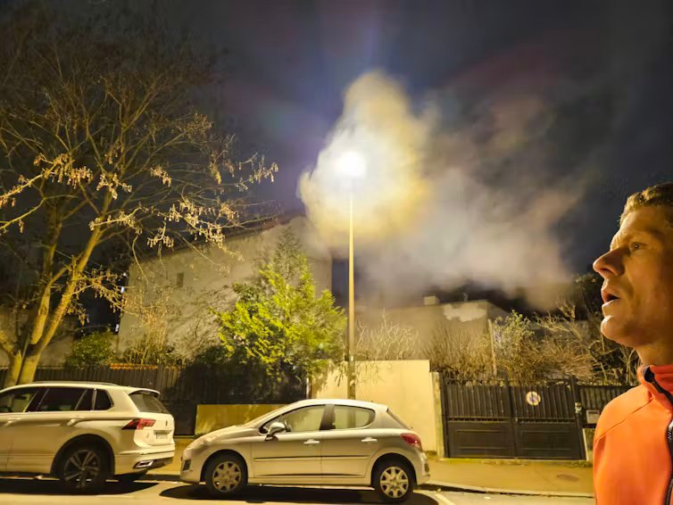 homme soufflant devant un lampadaire et formant un nuage de condensation