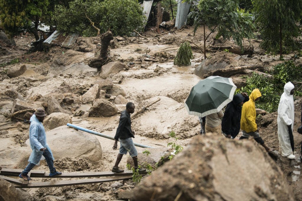 Des civils traversent une rivière après le second passage du cyclone Freddy au Malawi, le 13 mars 2023. Le changement climatique rend les évènements météorologiques (cyclones, sécheresses...) plus fréquents, longs, intenses et précoces.