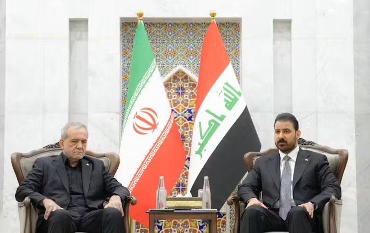 Two leaders in suits sit side by side flanked by national flags.