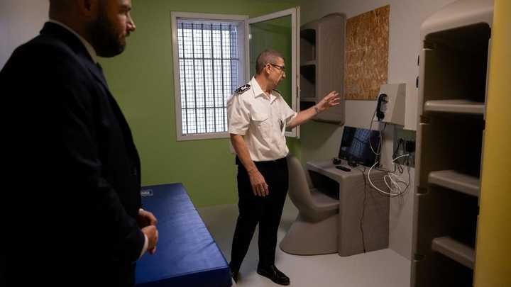Olivier Pipino (au centre), directeur de la prison de Réau, présente une cellule du nouveau QLCO, le 30 juillet 2026. (LOU BENOIST / AFP)