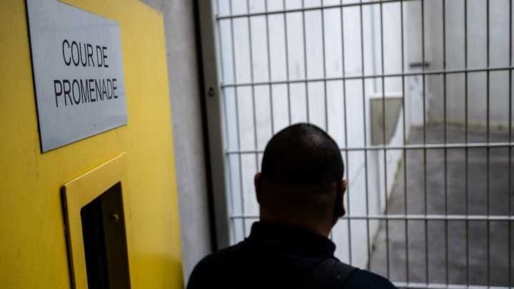 Un surveillant pénitentiaire se tient devant la cour de promenade du futur QLCO de Réau, le 30 juillet 2026. (LOU BENOIST / AFP)